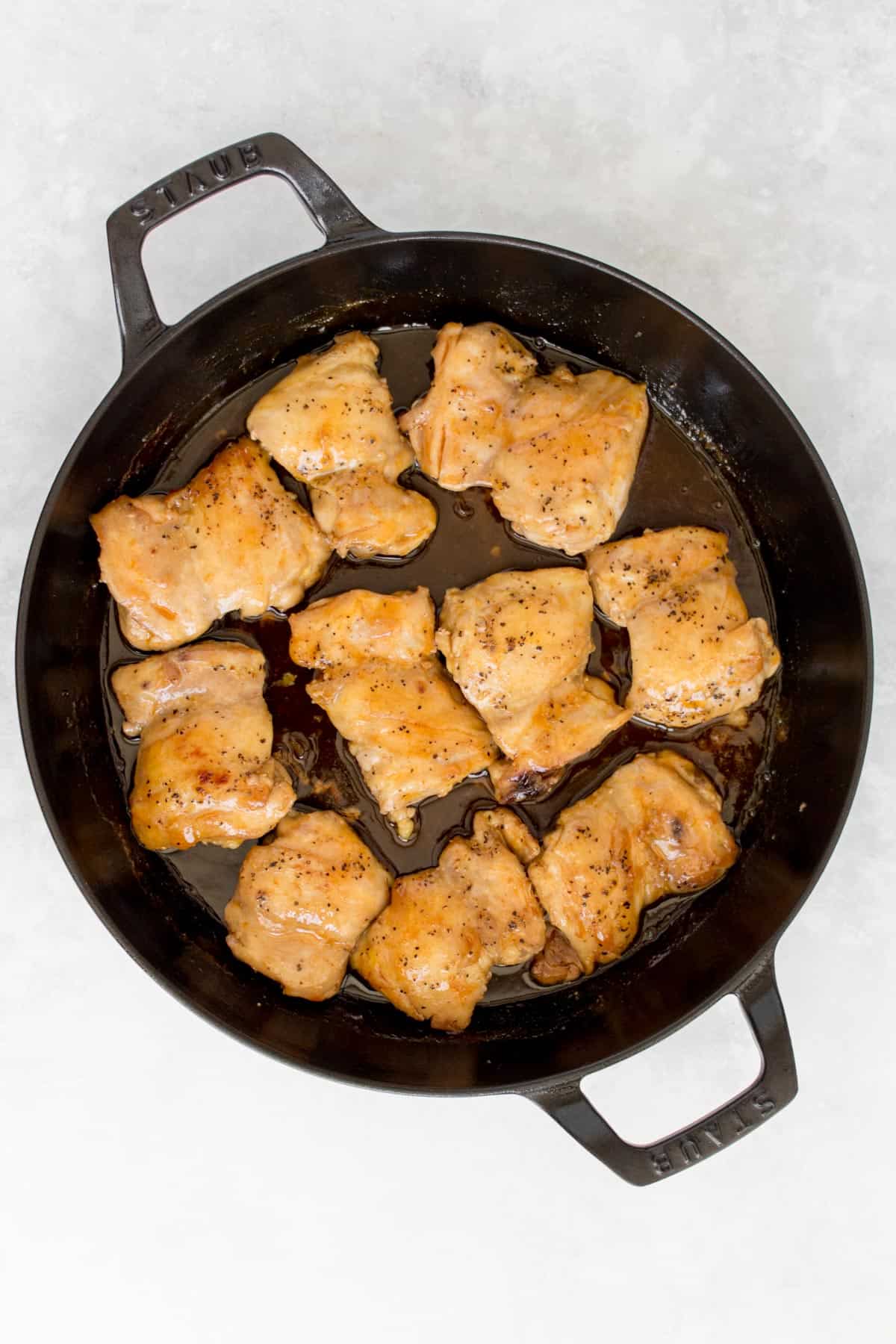 A cast iron pan with cooked honey sriracha lime chicken thighs.