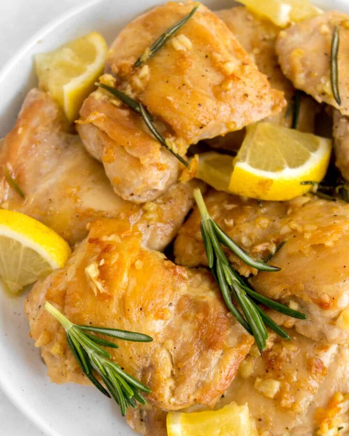 A white plate with multiple lemon rosemary butter chicken thighs.
