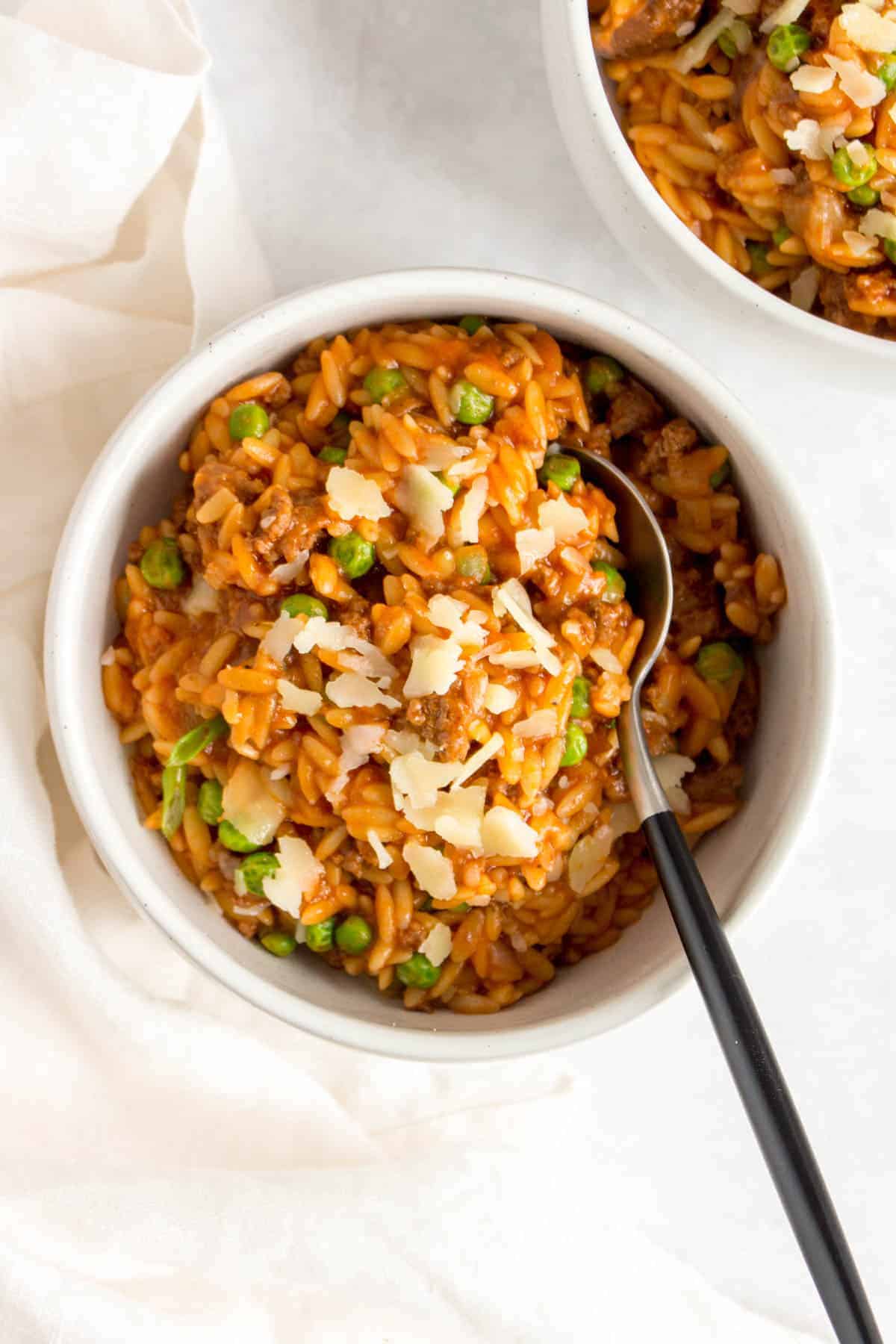 Overhead view of a bowl of beef, tomato, orzo with a spoon.