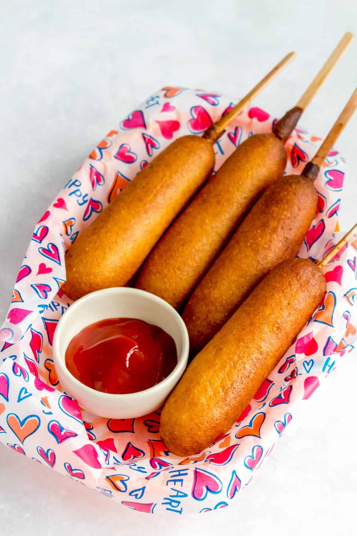 A basket of four air fryer corn dogs with a serving of ketchup.