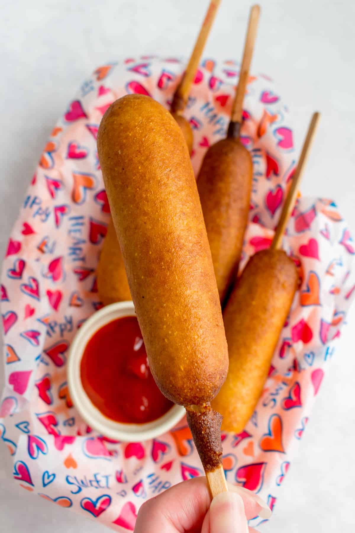 A corn dog being held up.