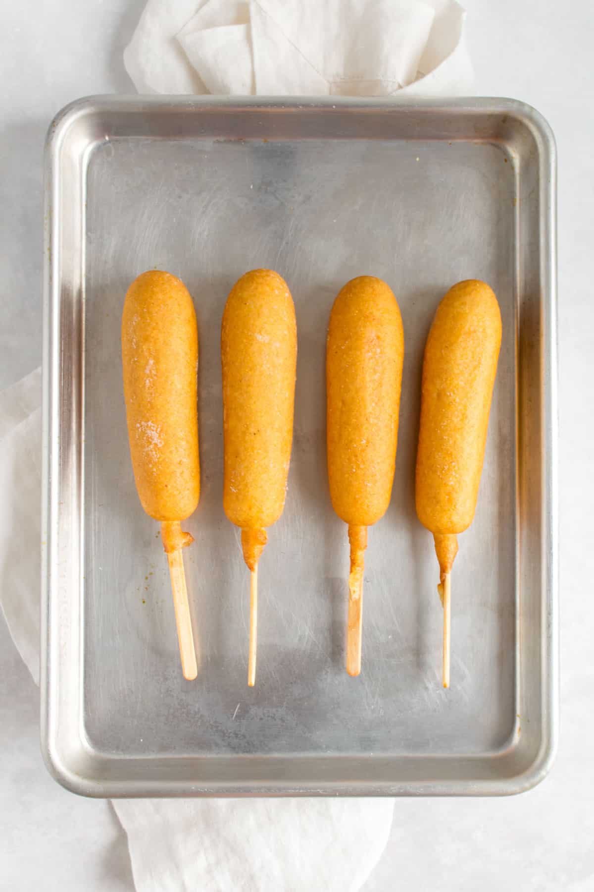 Frozen corn dogs on a sheet pan, uncooked.