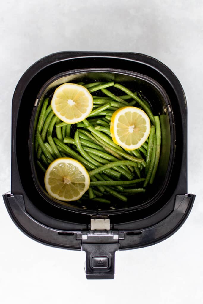 Seasoned green beans in the air fryer, before cooking.