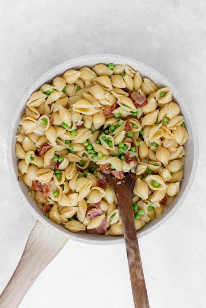Pan of pasta with bacon and peas.