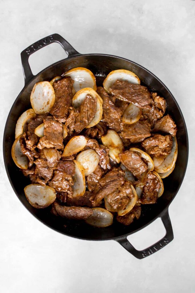 Beef and onions stir fry in a cast iron.