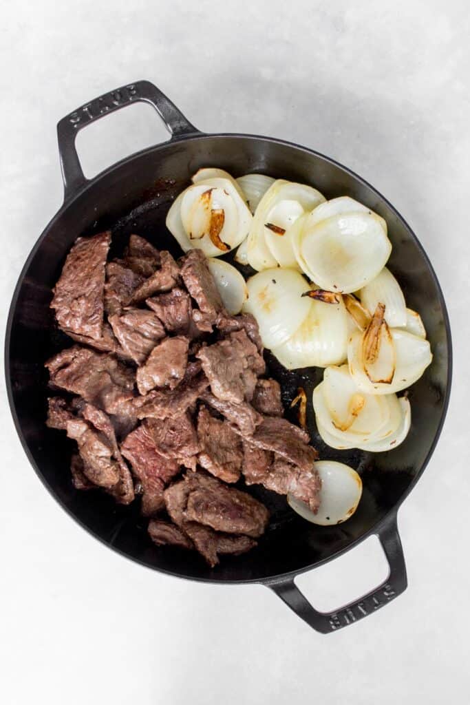 Beef and onions in a cast iron.