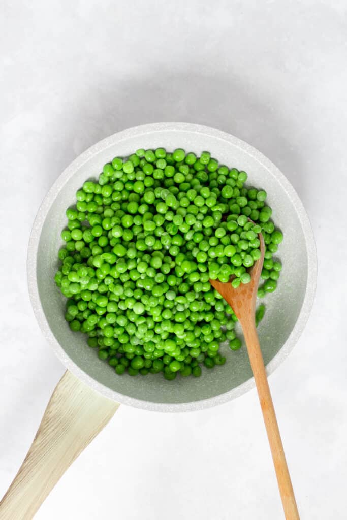 Peas added to the skillet of butter and garlic.