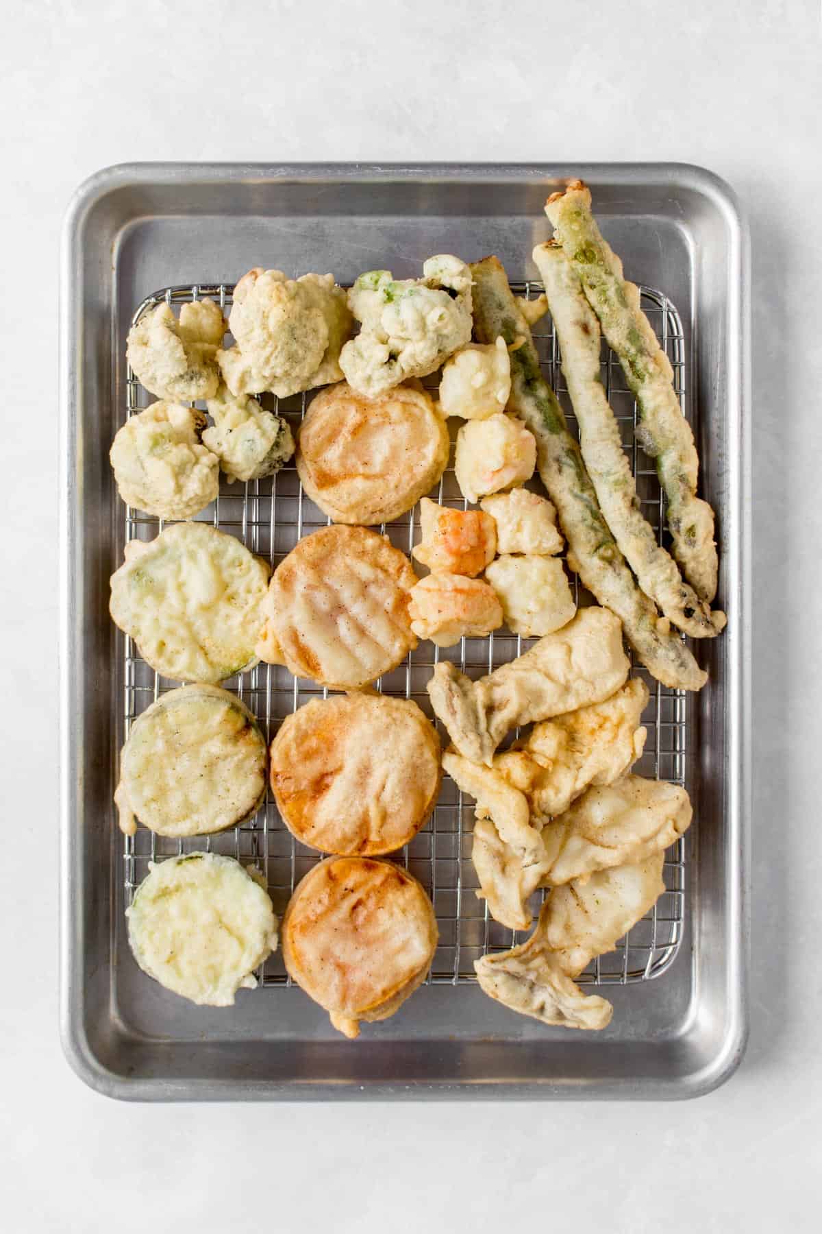 Mixed tempura on a cooling rack on a sheet pan.