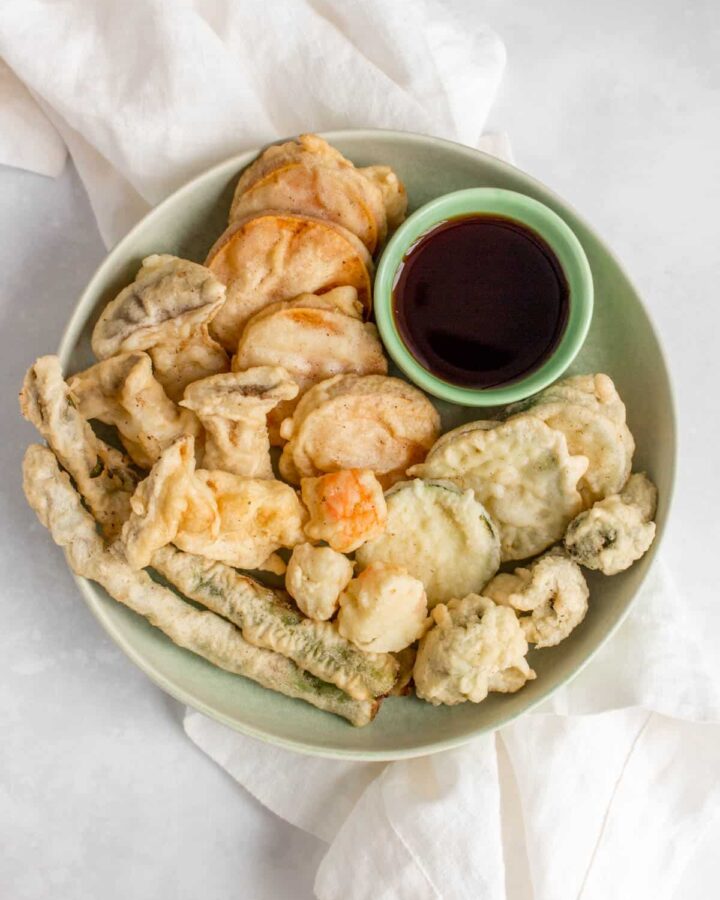 Plate of mixed vegetable tempura with dipping sauce.
