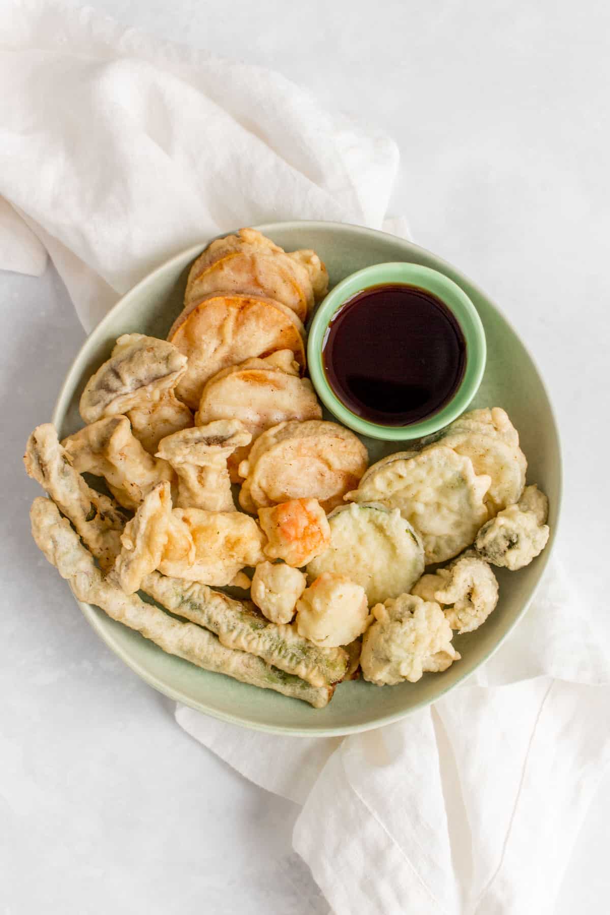 Plate of mixed vegetable tempura with dipping sauce.