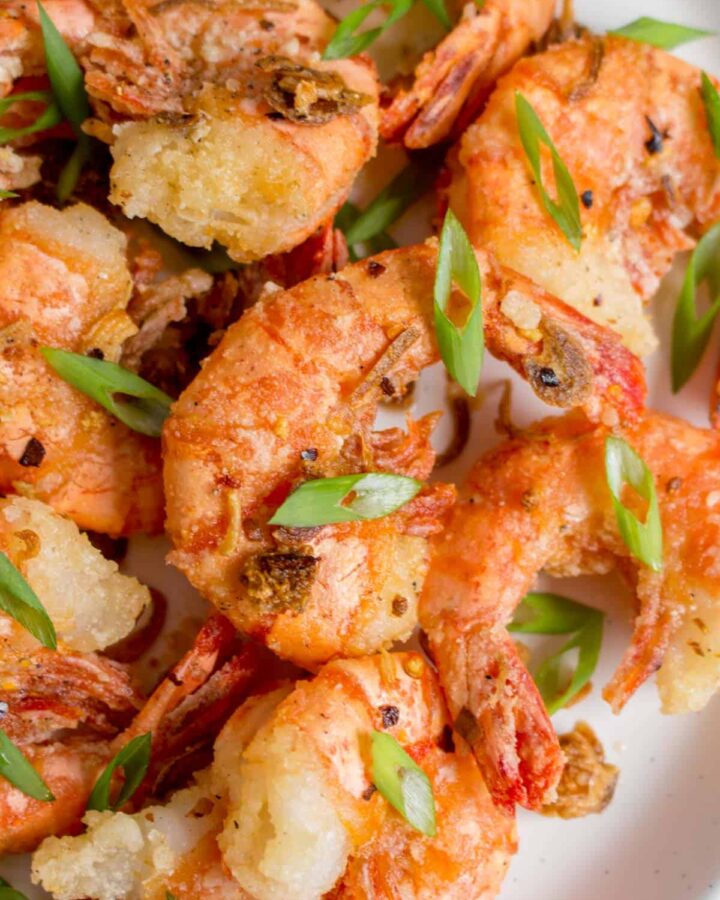 Close up of a salt and pepper shrimp with green onions on top.