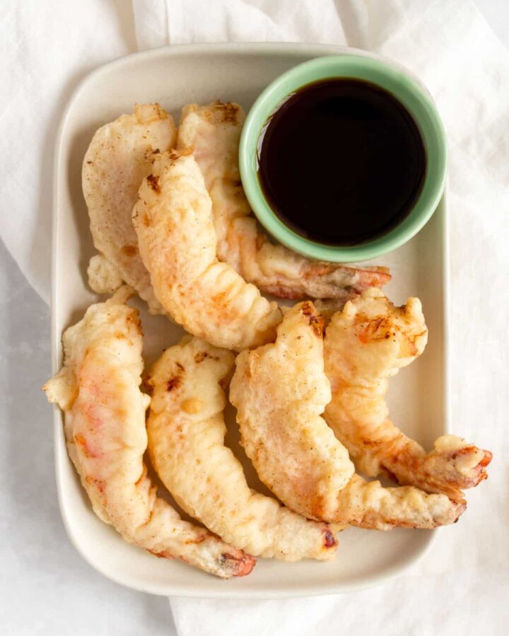 A platter of shrimp tempura with a bowl of dipping sauce.