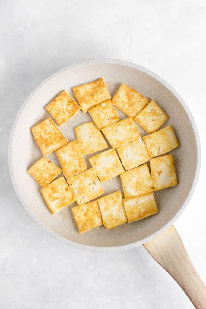 Pan-fried tofu in a pan.