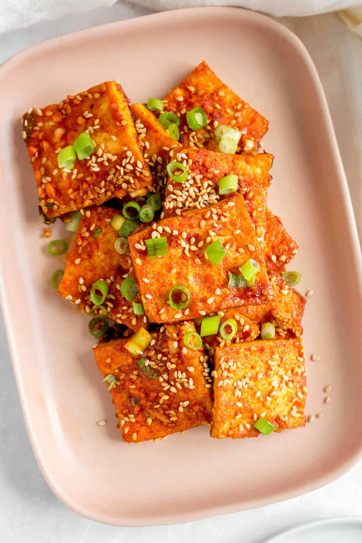 Close up of braised tofu in a pink plate.