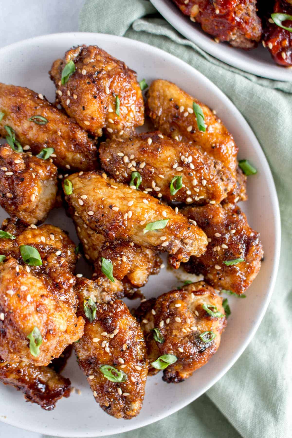 Close up of a plate of Korean air fryer chicken wings coated in a soy garlic glaze.
