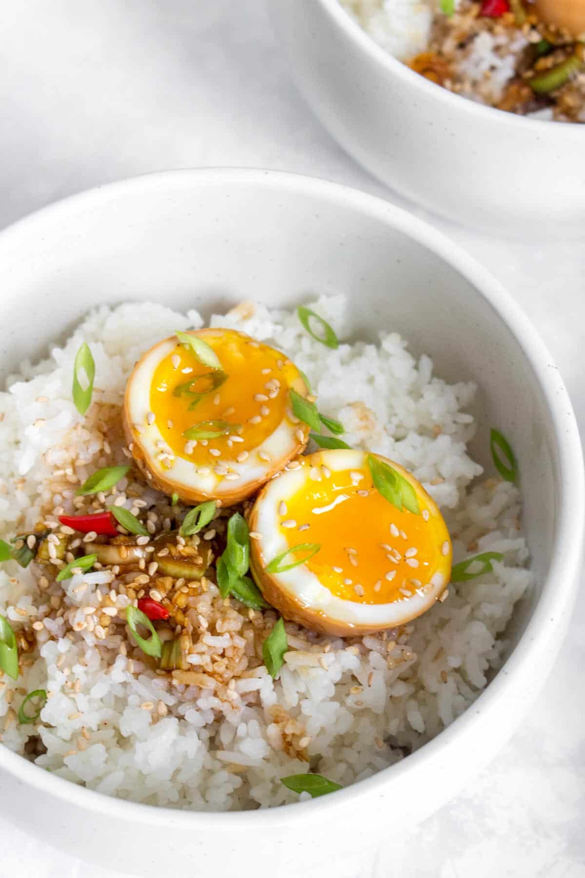 Close up of a Korean marinaded egg, cut in half, in a bowl of rice.