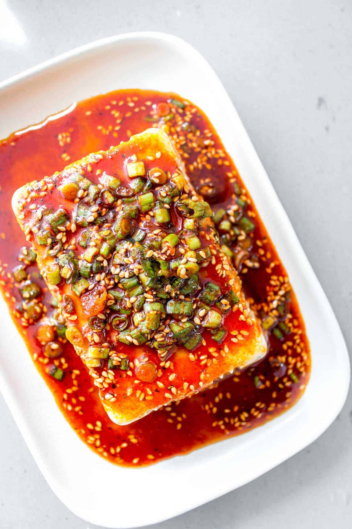 Overhead view of silken tofu with soy sesame sauce on top.