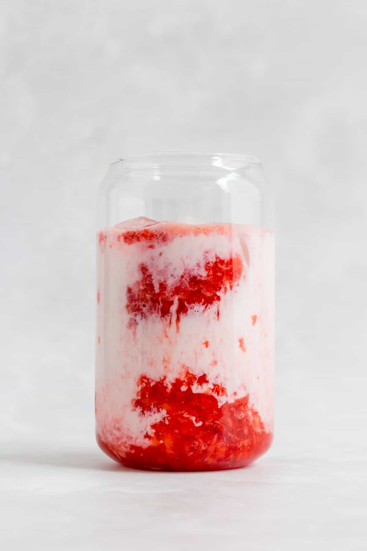 Milk added to the glass of strawberry puree.