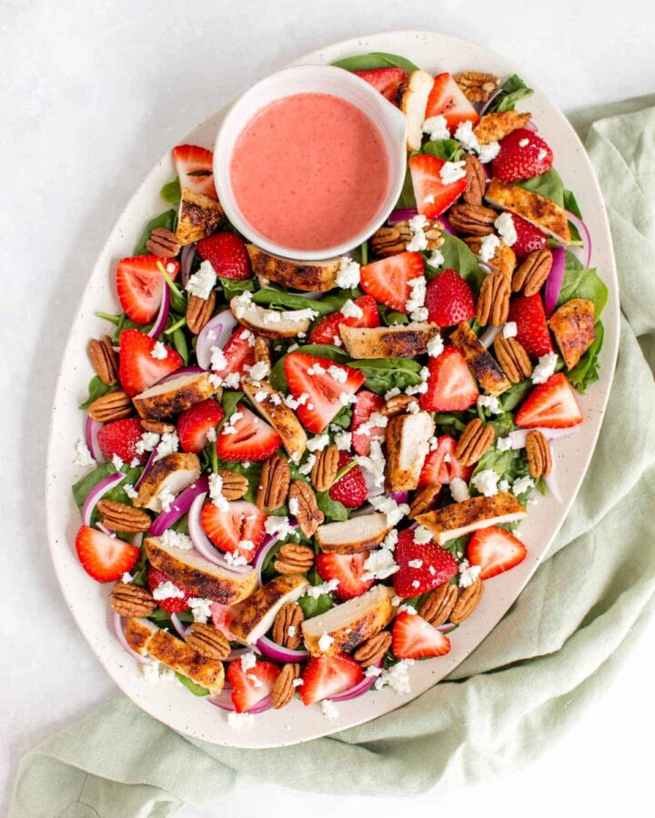Overhead view of a platter of strawberry spinach salad.