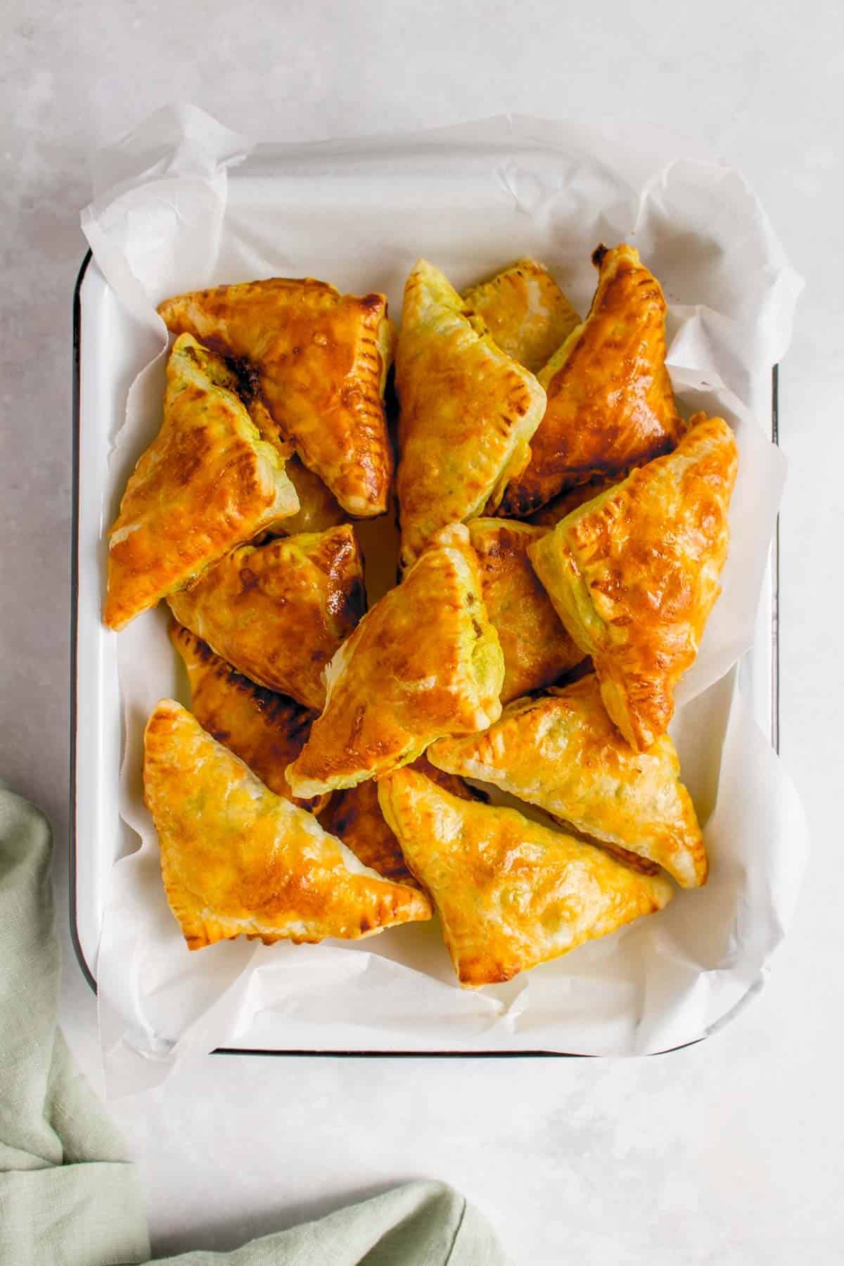 Beef curry puffs in a lined tray.