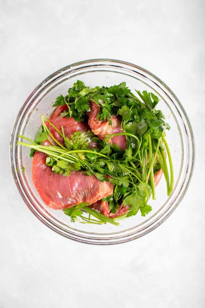 A bowl with flank steak in marinate.