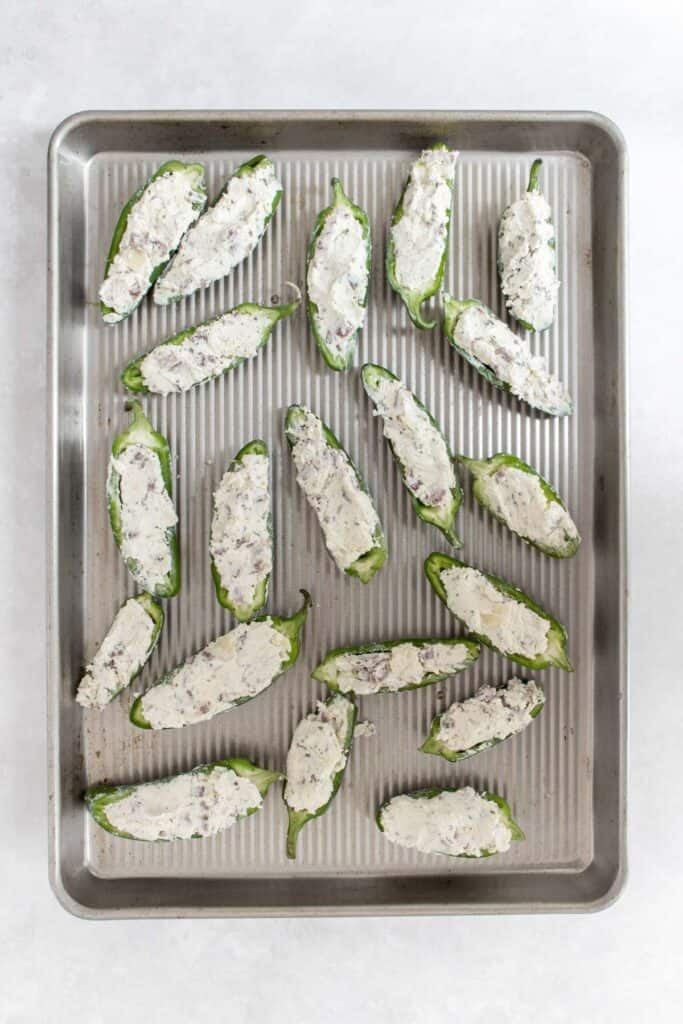 A sheet pan with jalapeno stuffed with a cheese mixture.