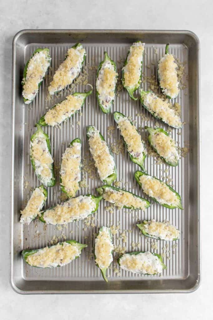 Sheet pan with jalapeno poppers on top before baking.