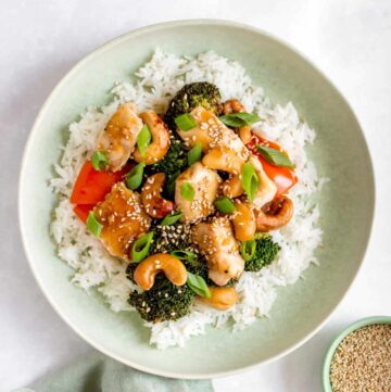 Sheet pan cashew chicken over a bed of rice in a green plate.