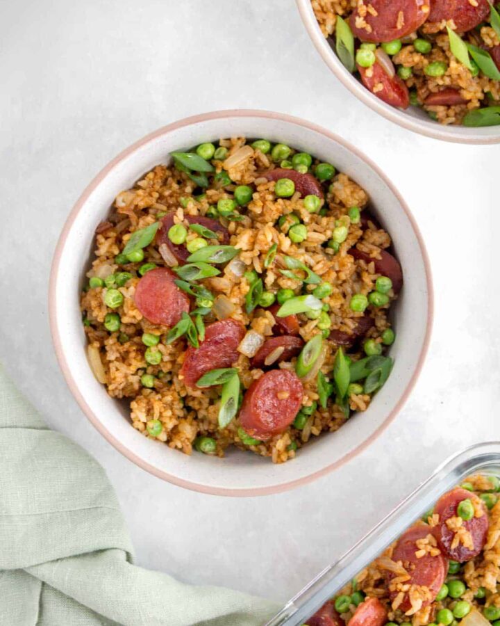 A bowl of Chinese sausage fried rice with sliced green onions on top.