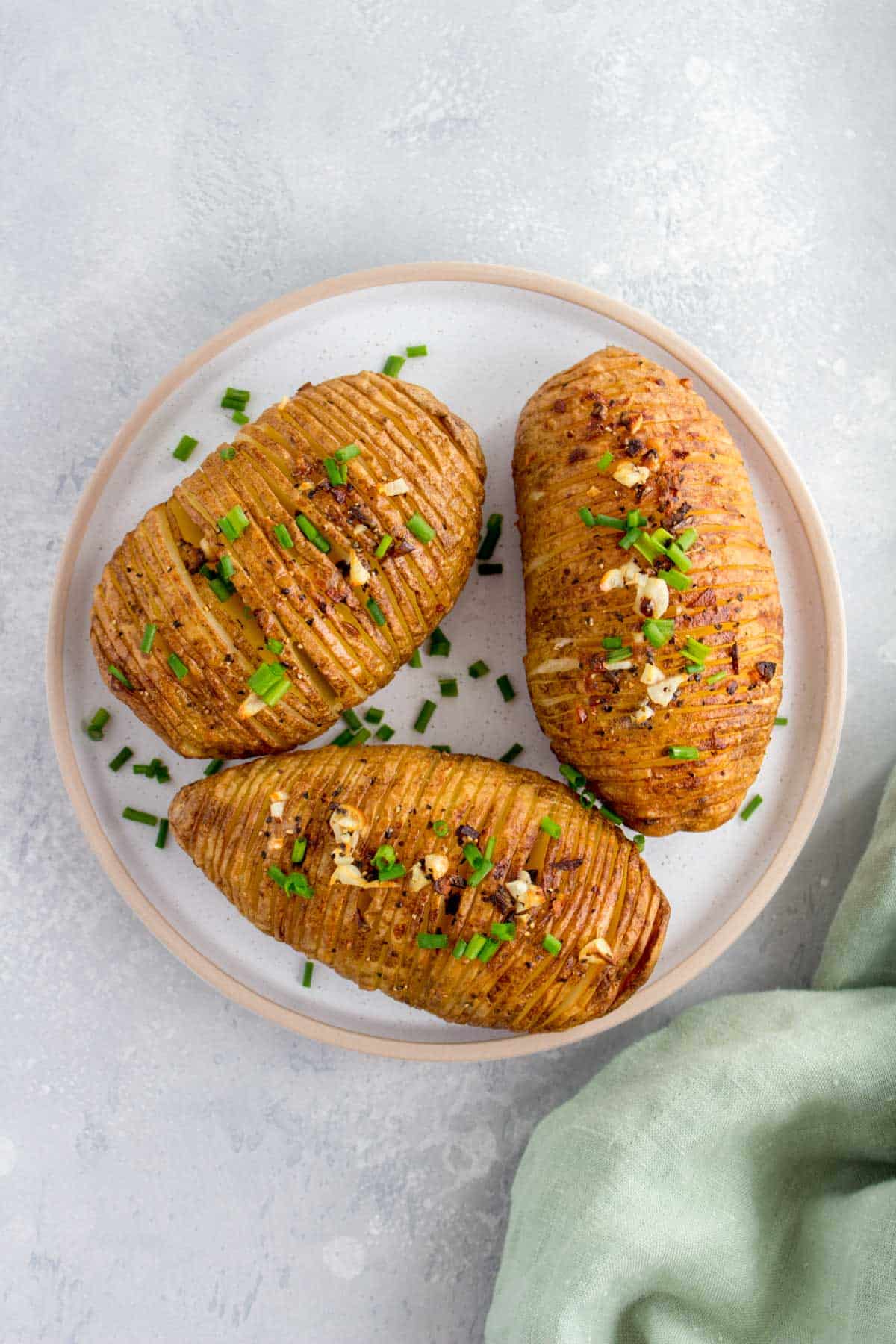 Overhead view of a plate of three air fryer hasselback potatoes.