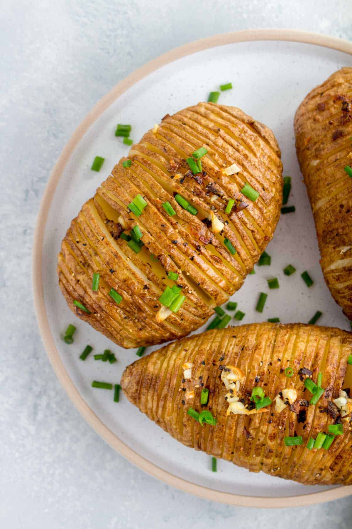 Close up of a plate of three air fryer hasselback potatoes.