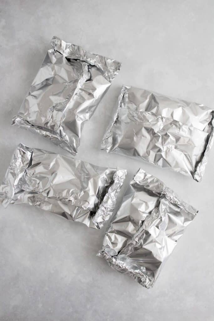 Four packets of steak and potatoes foil packet.