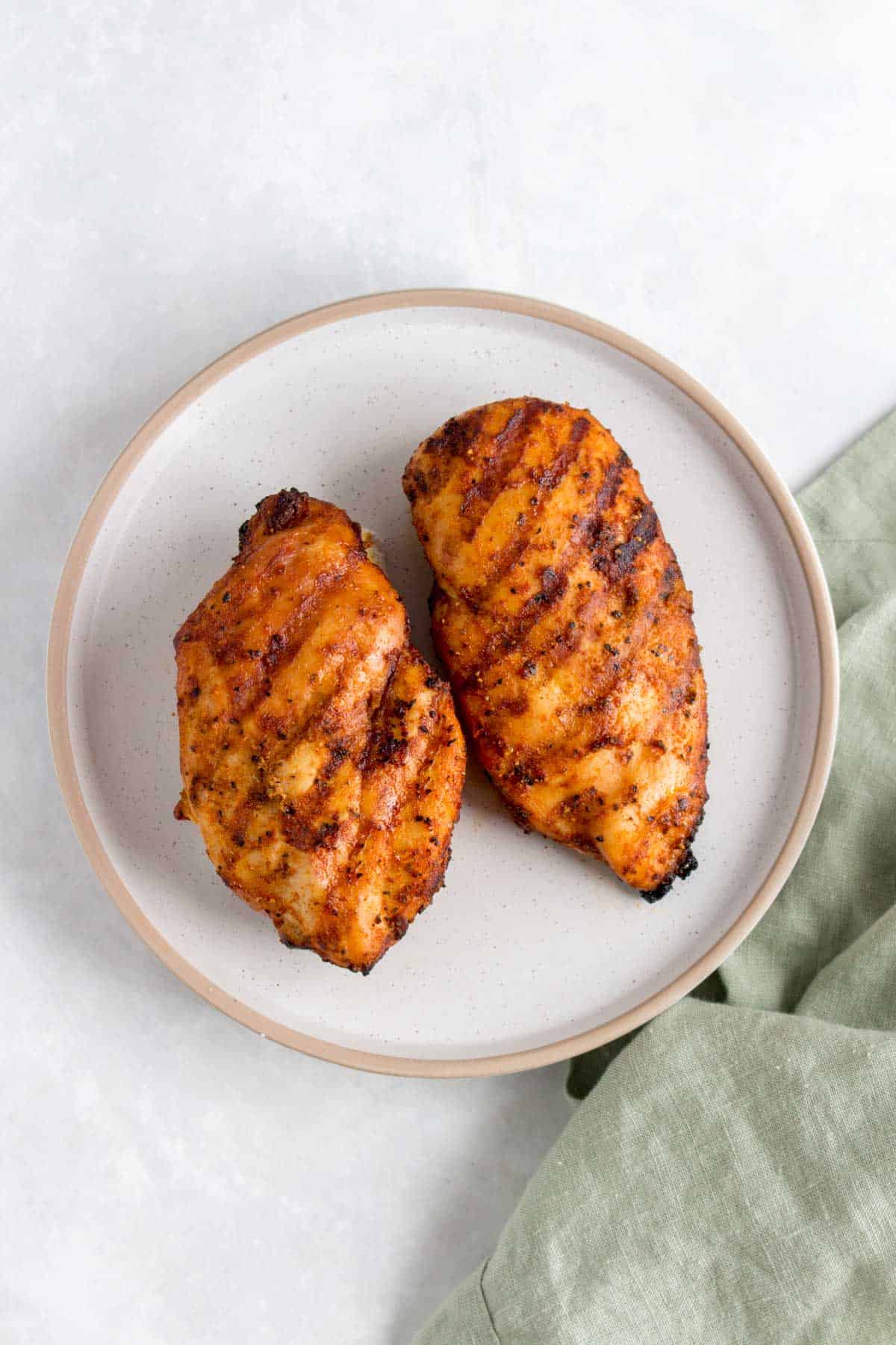Two grilled chicken breasts on a plate.