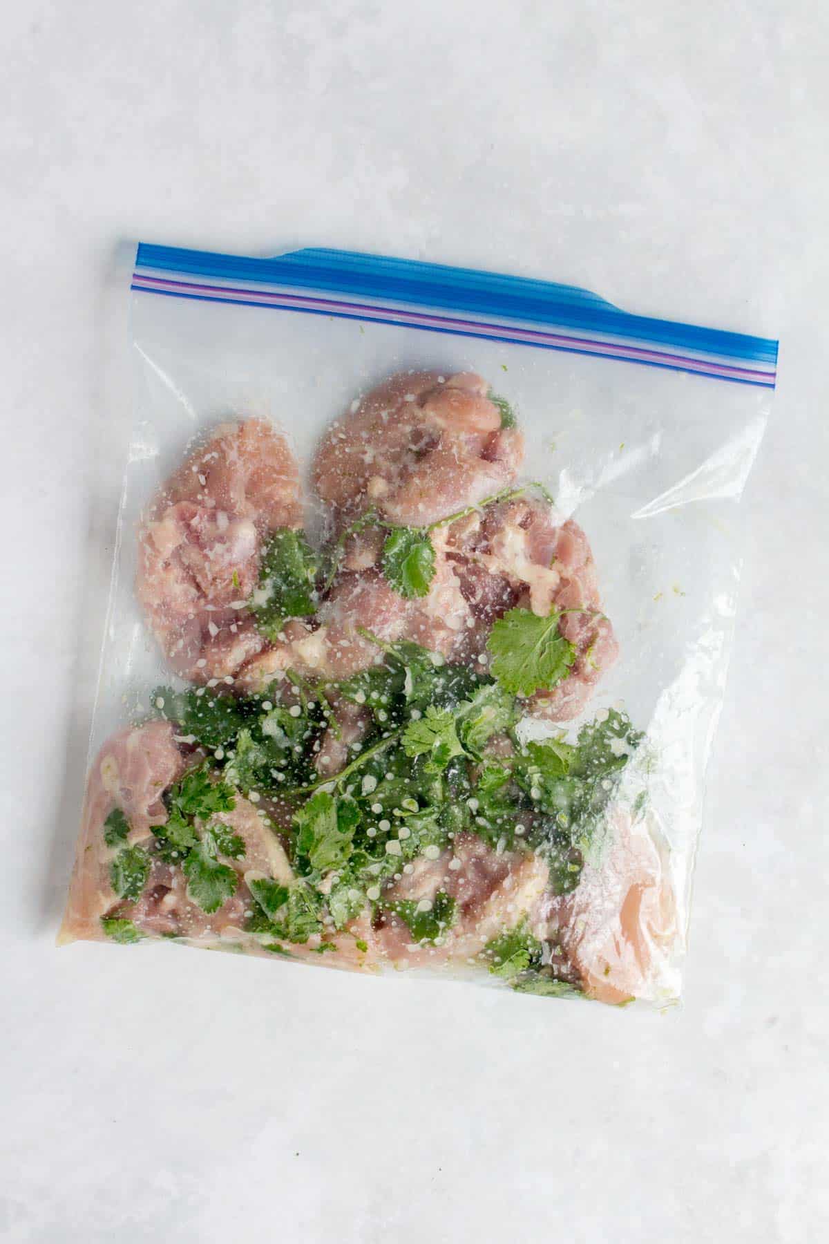 A ziploc bag with chicken thighs with cilantro lime marinade.