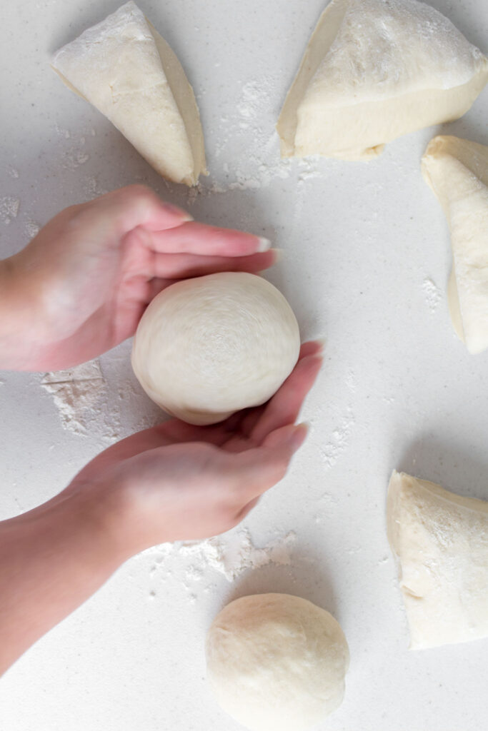 Dough ball being shaped to be more round.