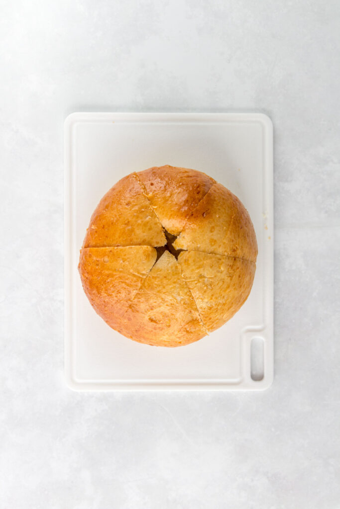 Overhead view of bread bun with 6 wedges cut.