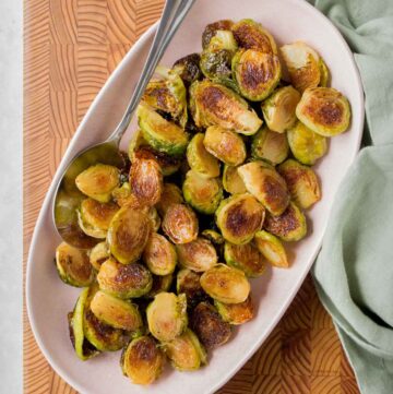 Maple glazed roasted brussels sprouts in a platter with a spoon.