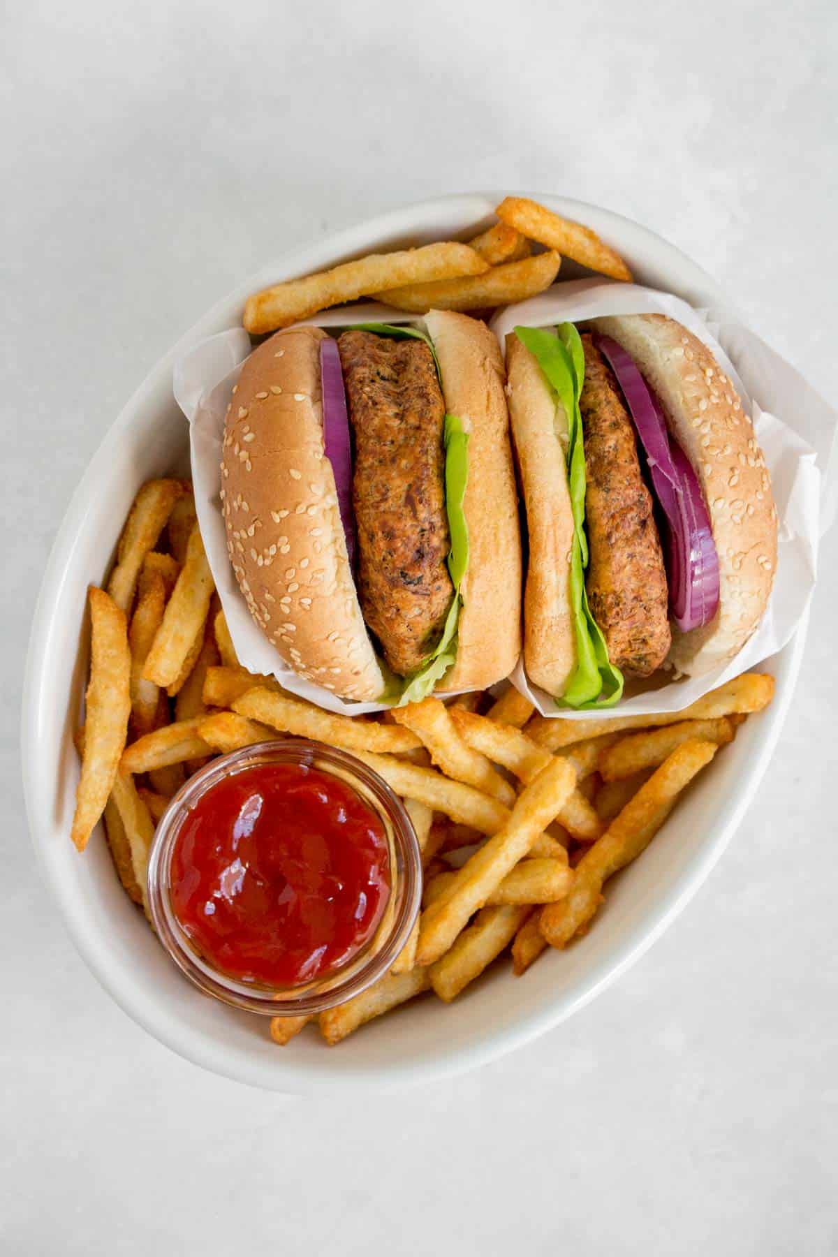 Overhead view of a serving dish with two turkey burgers, fries, and ketchup