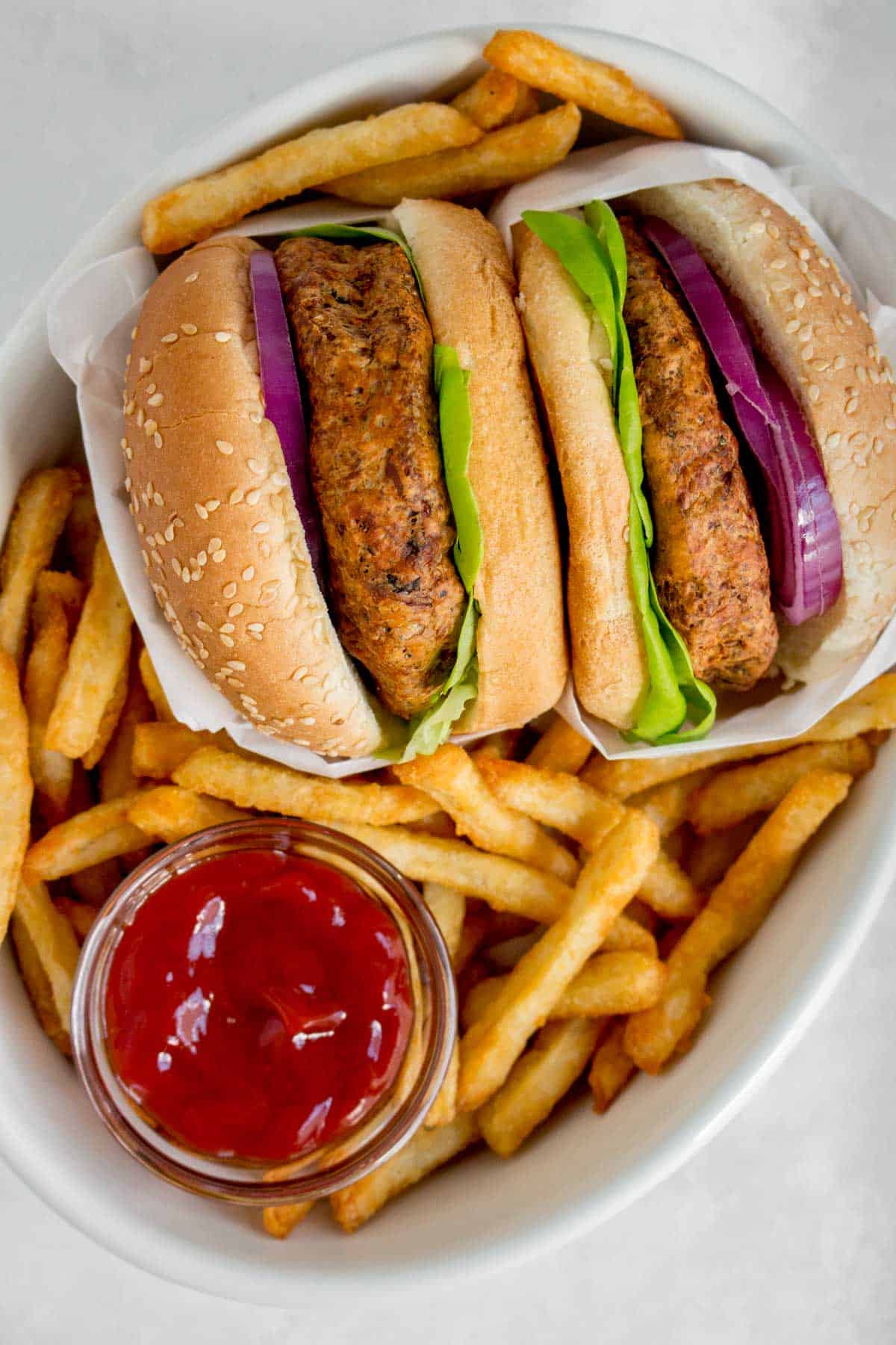 Close up of two turkey burgers with fries and ketchup.