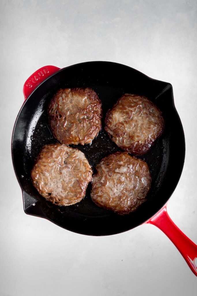 Burger patties in a cast iron skillet.