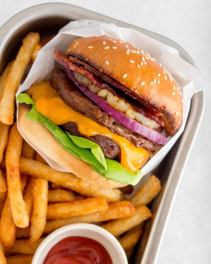 A serving tray with an aloha burger with fries and ketchup.