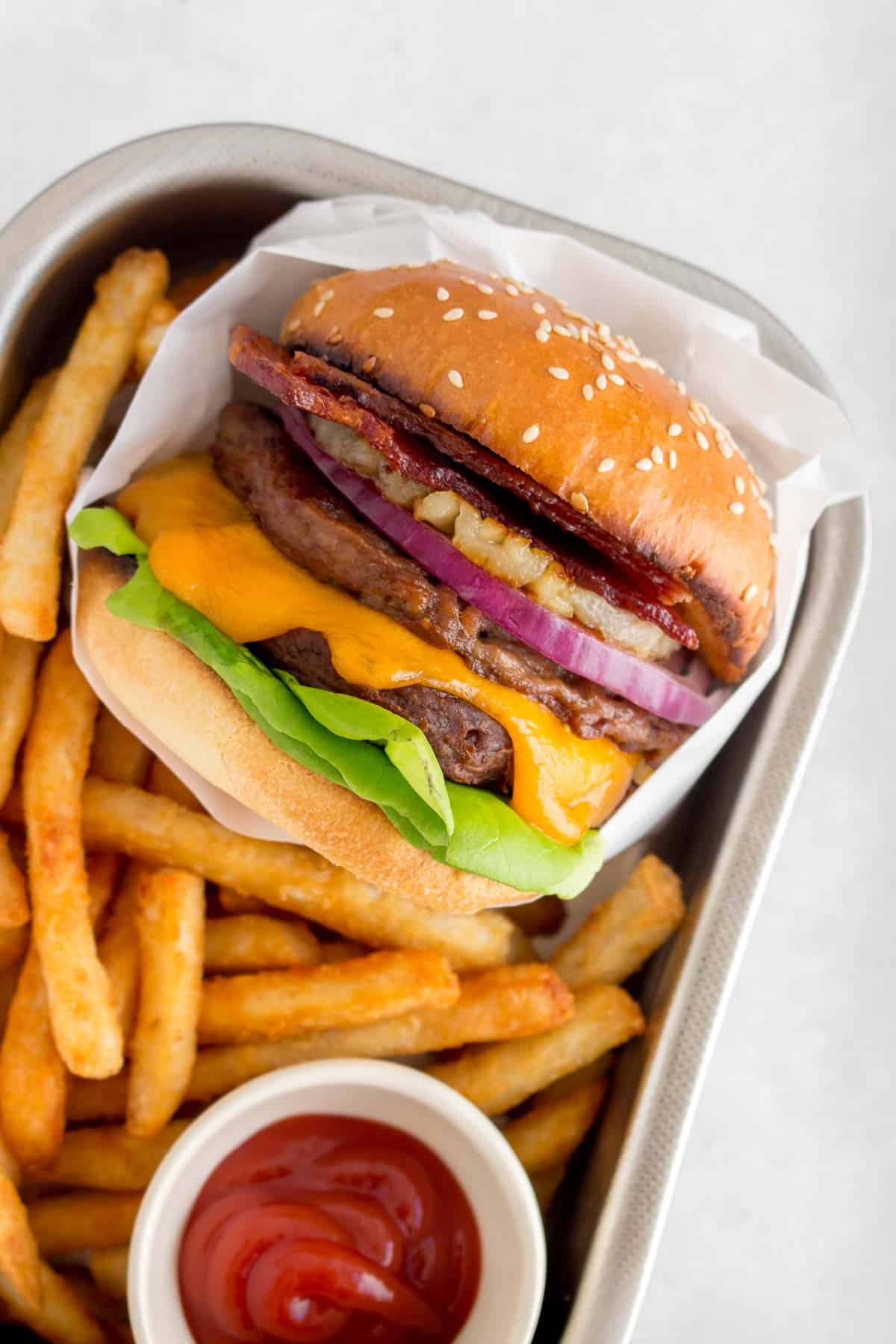 A serving tray with an aloha burger with fries and ketchup.