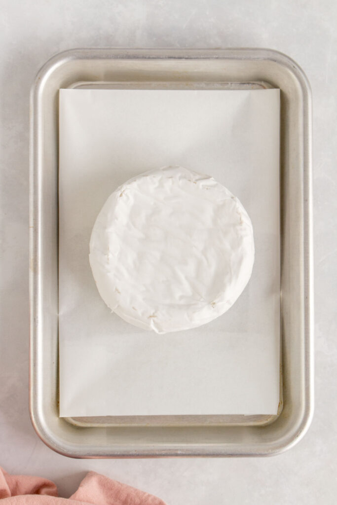 A wheel of brie on a sheet pan.