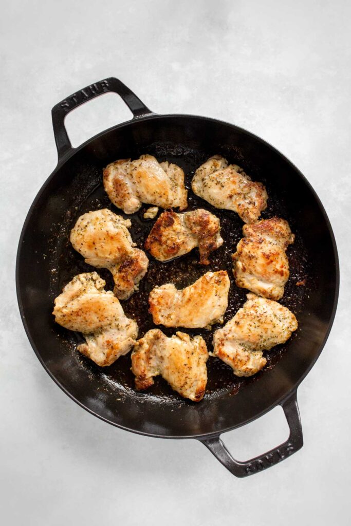 Pan seared Greek chicken thighs in a cast iron.