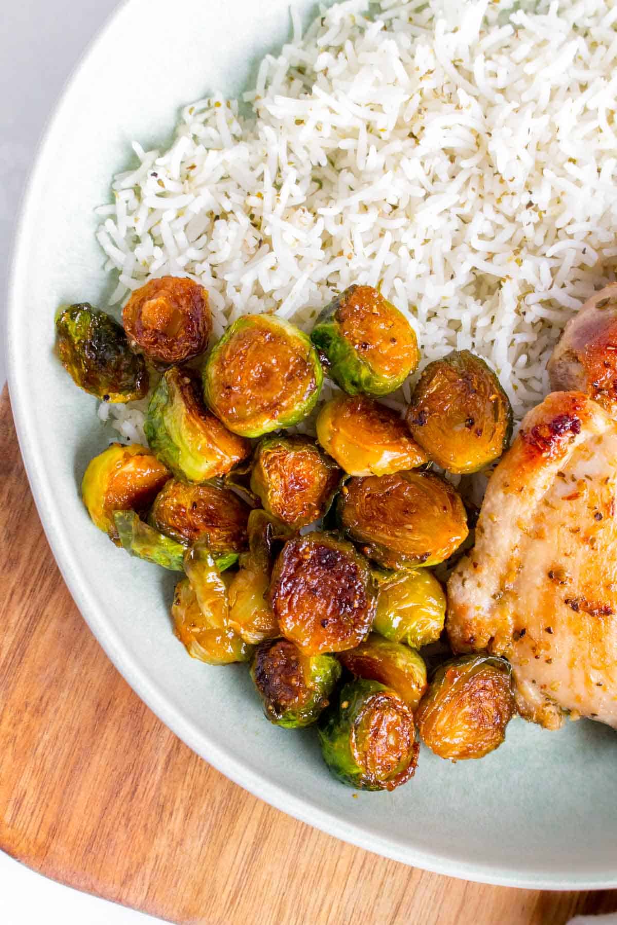 A bowl of rice and chicken with honey sriracha brussels sprouts.