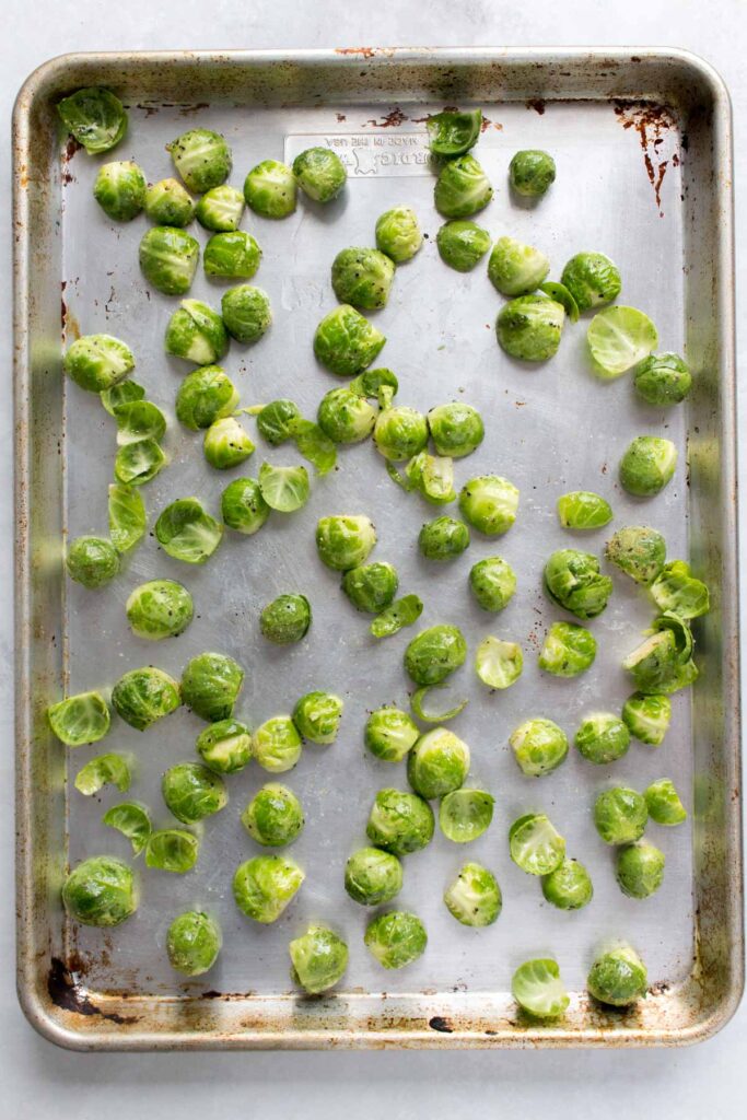 A sheet pan with brussels sprouts, cut side down.