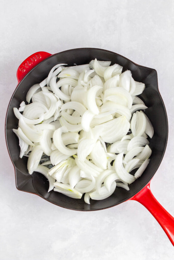 Sliced onions added to a pan of melted butter and olive oil.