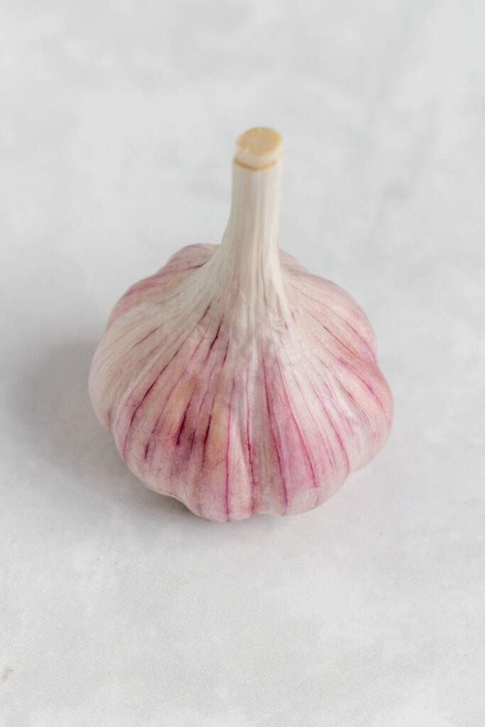 A bulb of garlic with the papery outer layer removed.