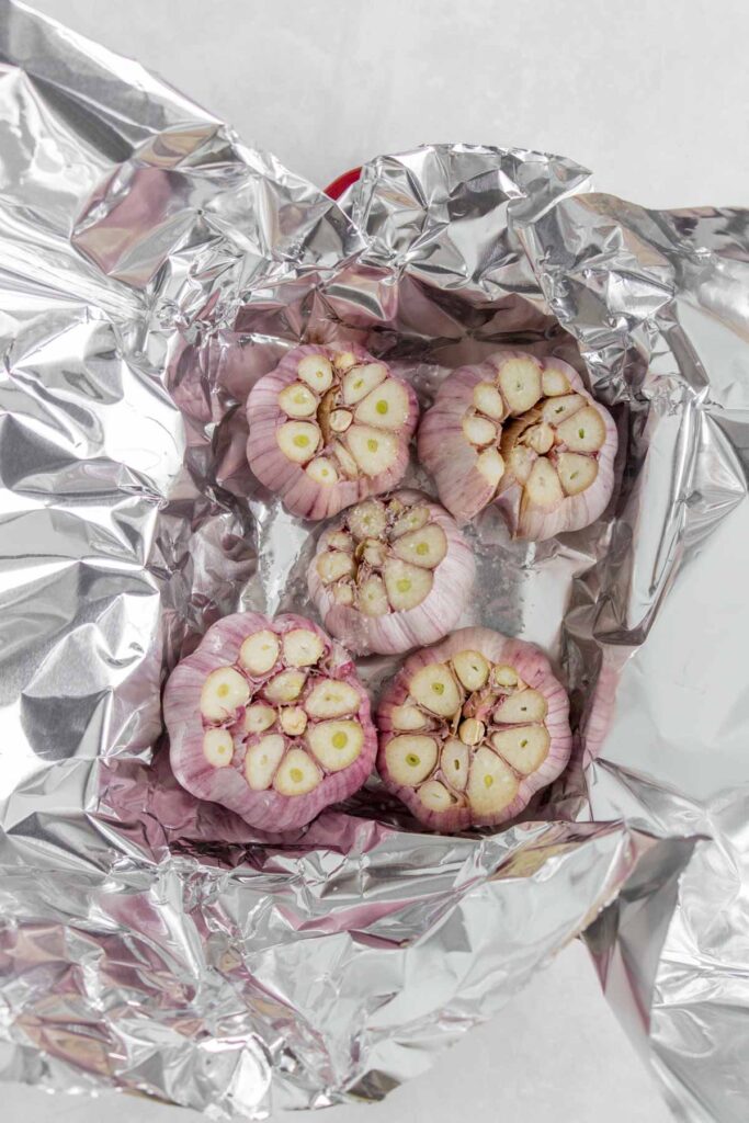 Garlic added to tin foil with olive oil and salt added on top.