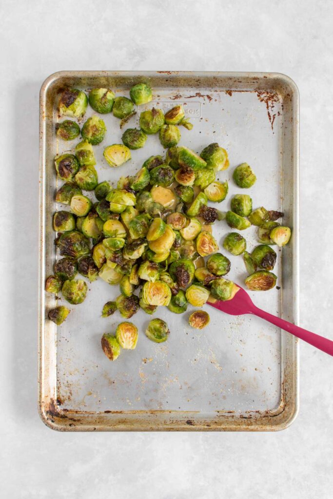 Maple mustard added to a sheet pan with brussels sprouts.
